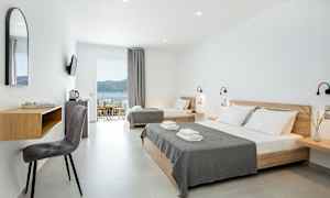 Modernt hotellrum med ljusa väggar, dubbelsäng och enkelsäng samt havsutsikt. (AI-genererad text)