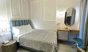 Ett hotellrum med en säng, ett nattduksbord och en spegel. (AI-genererad text)