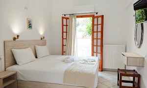 Ett hotellrum med en dubbelsäng och öppen balkongdörr. (AI-genererad text)