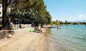 En strand med solstolar, badbrygga och klara blått vatten. (AI-genererad text)