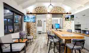 En interiörbild av ett kontor med sittgrupp, skrivbord och dekorativ stenvägg. (AI-genererad text)