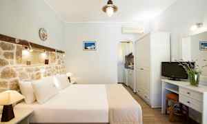 Hotellrum med dubbelsäng, stenmur och mindre köksdel. (AI-genererad text)