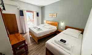 Hotelrum med två enkelsängar, ett skrivbord och en balkong. (AI-genererad text)