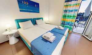 Ett hotellrum med två enkelsängar, blå sängkläder och en tavla ovanför. (AI-genererad text)