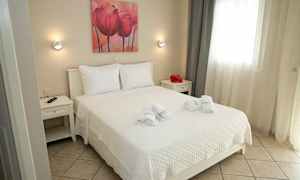 Ett ljus och välordnat sovrum med en dubbelsäng, vita sängkläder och nakenfärgad inredning. (AI-genererad text)