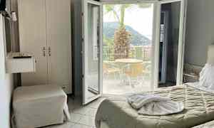 Hotellrum med utsikt mot en terrass med bord, stolar och en palm. (AI-genererad text)