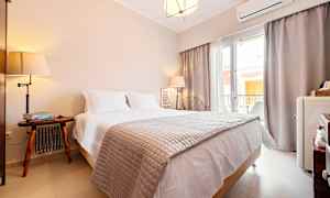 Ett hotellrum med en dubbelsäng, nattduksbord och fönster som släpper in naturligt ljus. (AI-genererad text)