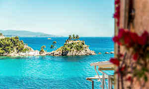 En liten ö med träd och ett hus omgiven av blått vatten. (AI-genererad text)