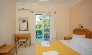 Ett hotellrum med en bäddad säng, ett skrivbord och en stol, samt en glasdörr som leder till en balkong. (AI-genererad text)