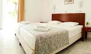 Bild av ett hotellrum med en dubbelsäng, uppställda vita handdukar och ett glas med dryck på nattduksbordet. (AI-genererad text)