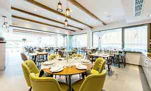 En restaurang med många dukade bord och stolar. (AI-genererad text)