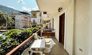 Balkong med bord och stolar samt utsikt över ett bostadsområde med hus. (AI-genererad text)