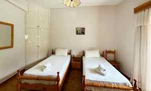 Bild av ett hotellrum med två enkelsängar och vita sängkläder, belägna vid en ljus vägg med ett litet väggskåp. (AI-genererad text)