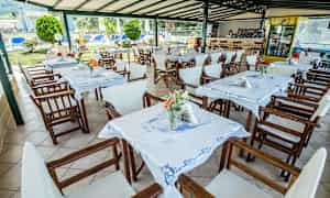 Utomhus restaurangområde med bord och stolar samt dekorationer. (AI-genererad text)