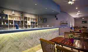 Bar med träbord och hyllor fyllda med flaskor. (AI-genererad text)