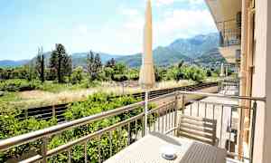 En balkong med utsikt över en grönskande dalgång och berg i bakgrunden. (AI-genererad text)