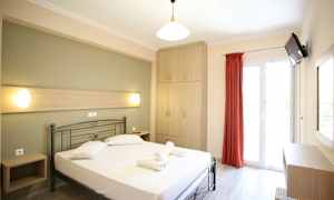 Ett ljust hotellrum med en säng, skåp och en balkongdörr. (AI-genererad text)