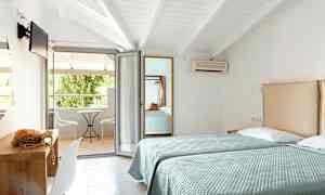 Två enkelsängar i ett hotellrum med öppning mot en möblerad balkong. (AI-genererad text)