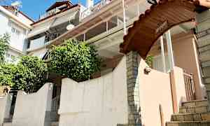 Ett flerfamiljshus med flera balkonger, en välvd port med skylten 'Giovanni' och grönska vid ingången. (AI-genererad text)