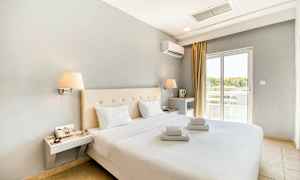 Modernt möblerat hotellrum med dubbelsäng och vita lakan. Fönster med ljusinsläpp. (AI-genererad text)