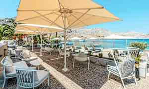 En terrass med sittmöbler och parasoller vid havet. (AI-genererad text)