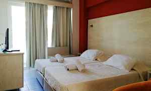 Ett hotellrum med två enkelsängar och en röd vägg bakom dem. (AI-genererad text)