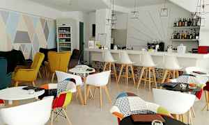 Inomhusvy av ett stilfullt café med färgglada stolar, ett barområde och dekorativa element. (AI-genererad text)