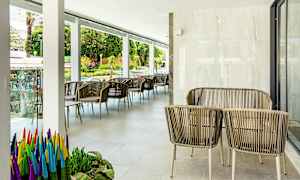 Utemöbler med rottingstolar och bord på en terrass, med växter och utsikt mot gatan. (AI-genererad text)