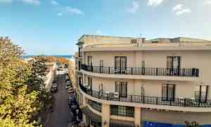 Vy över en gata med byggnader, en blå himmel syns i bakgrunden. (AI-genererad text)