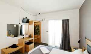 Ett hotellrum med en säng, garderob och ett skrivbord. (AI-genererad text)