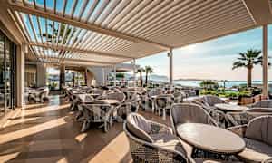 En utomhusterass med bekväma sittmöbler och utsikt över havet. (AI-genererad text)