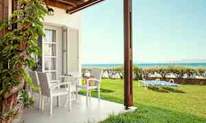 En uteplats med bord och stolar samt solstolar på gräsmatta nära havet. (AI-genererad text)