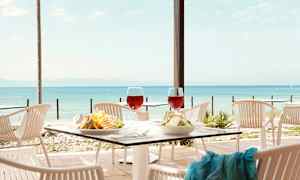 Bild av ett dukat bord vid en utomhusrestaurang med utsikt över havet. (AI-genererad text)