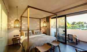 Ett sovrum med säng och mysig belysning, samt en terrass utanför. (AI-genererad text)