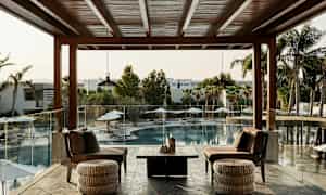 En terrass med sittmöbler som vetter mot en utomhuspool och palmer. (AI-genererad text)