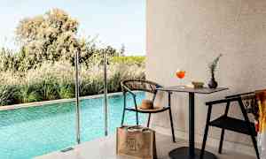 En utomhuspool med en sittgrupp och bord bredvid. (AI-genererad text)