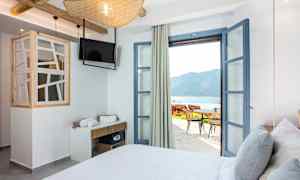 Hotellrum med öppna dörrar till terrass och havsutsikt. (AI-genererad text)