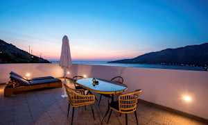 Terrass med bord, stolar och solstolar vid solnedgång. (AI-genererad text)