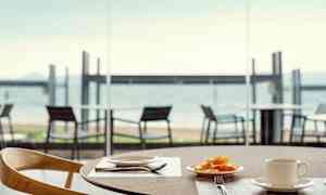 En tallrik med frukt och en kopp på ett bord, med utsikt över stranden. (AI-genererad text)