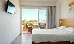 Hotellrum med dubbelsäng och balkong med sittmöbler. (AI-genererad text)