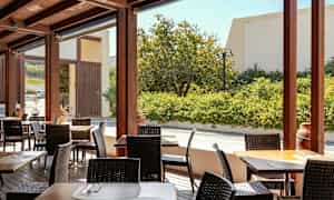 En utomhusterrass med bord och stolar, omgiven av grönska. (AI-genererad text)