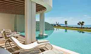 En utomhuspool med solstolar och utsikt mot havet. (AI-genererad text)