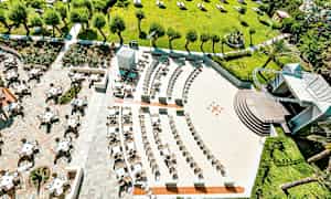 Flygvy av utomhussittplatser och grönområde med träd och parasoll. (AI-genererad text)