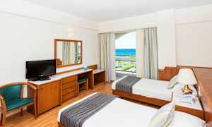 Hotelrum med två enkelsängar, skrivbord, stol och havsutsikt. (AI-genererad text)