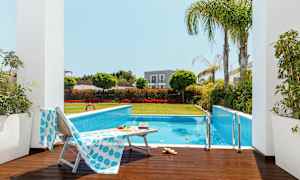 Utomhuspool omgiven av grönska och solstolar. (AI-genererad text)