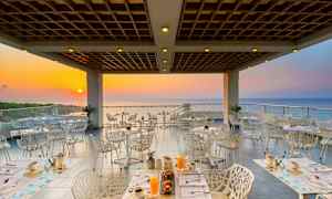 En restaurang med utsikt mot havet vid solnedgången. (AI-genererad text)