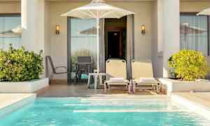 En privat terrass med solstolar, parasoll och en liten pool. (AI-genererad text)