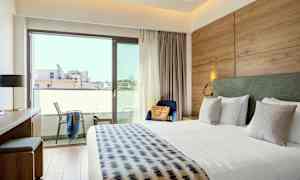 Ett hotellrum med en stor säng, skrivbord, stol och balkong. (AI-genererad text)