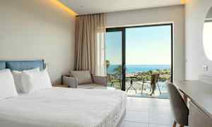 Hotellrum med säng, soffa och utsikt över havet. (AI-genererad text)