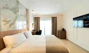 Hotellrum med bäddad säng, vägg-TV och skrivbord nära ett fönster. (AI-genererad text)